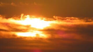 The sun going down behind a band of cloud, the whole sky in amber and orange.