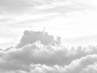 The same cloud faded almost to white, soft grey billows in a sky of the same light grey.